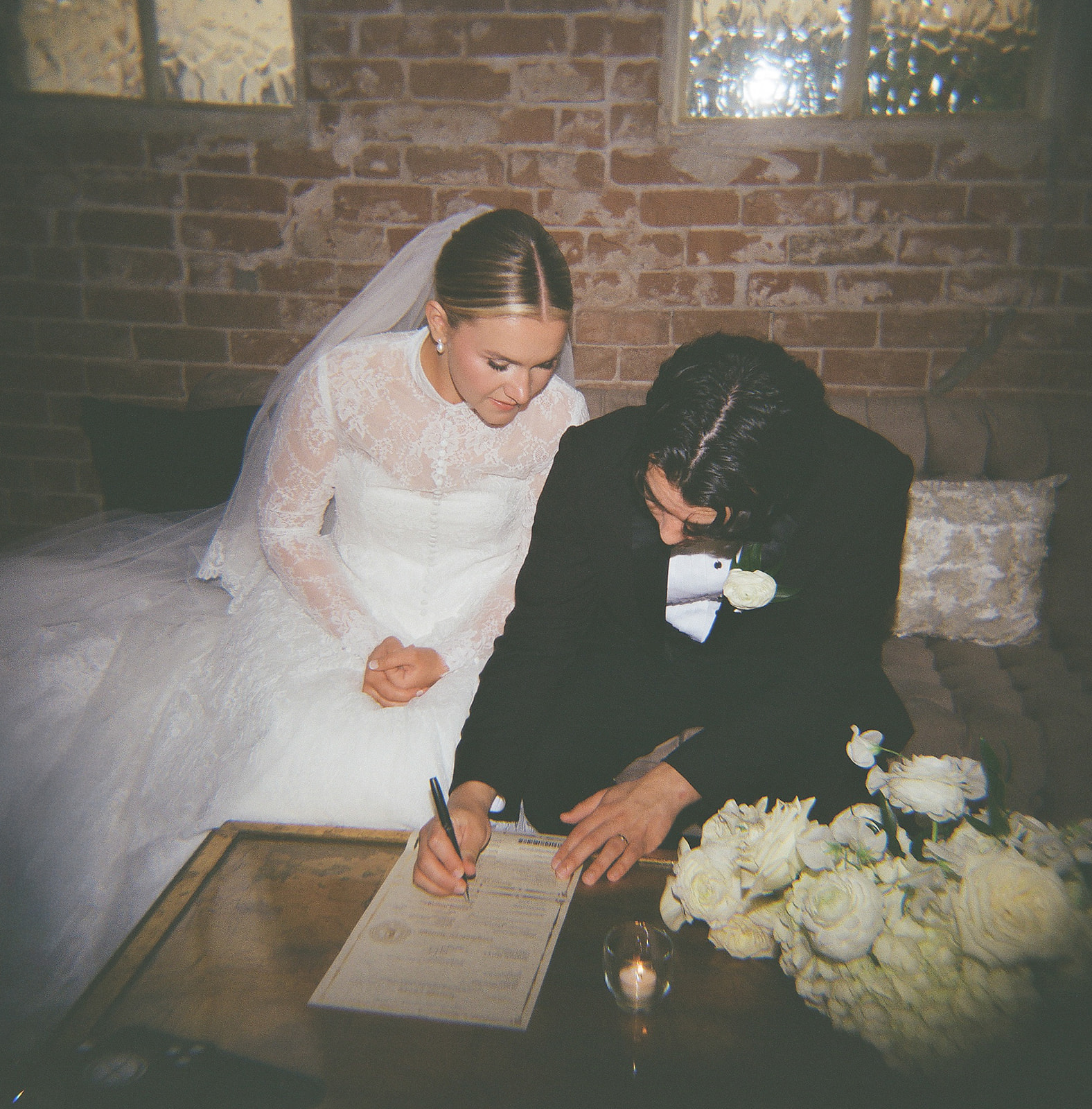 Film photo of a candid moment with bride and groom signing their marriage license. 