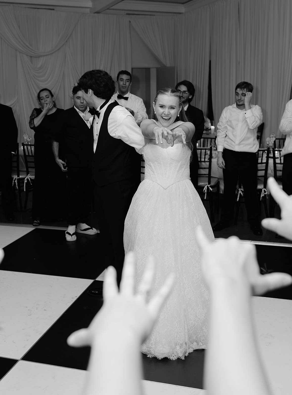 Bride and groom dancing on checkered dance floor during last reception song with guests. 