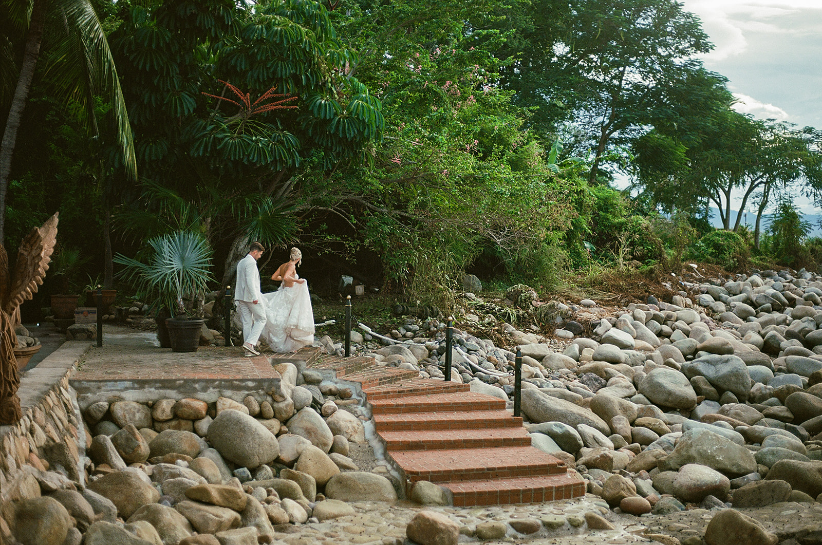 Couple walking along rocky coast during cinematic golden hour portraits taken on 35mm film