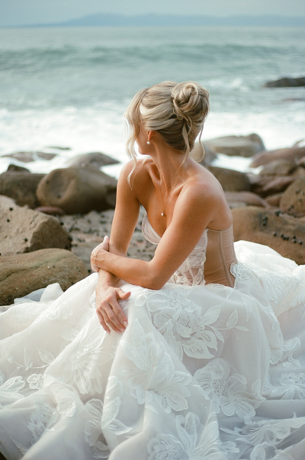 Editorial photo of bride sitting on rocky shoreline in Mexico taken on 35mm film