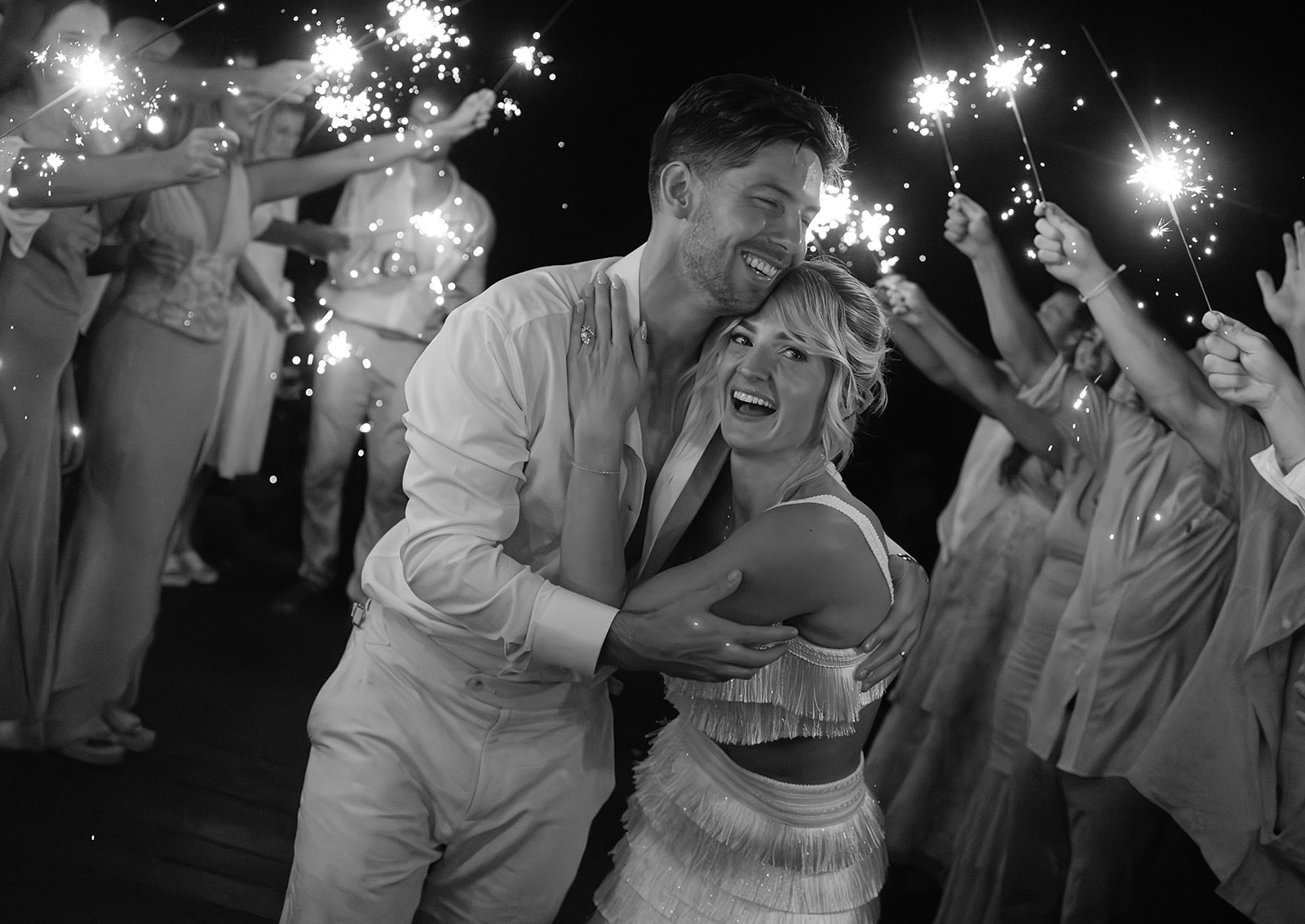 Couple embracing under night sky at destination wedding in Mexico with sparklers