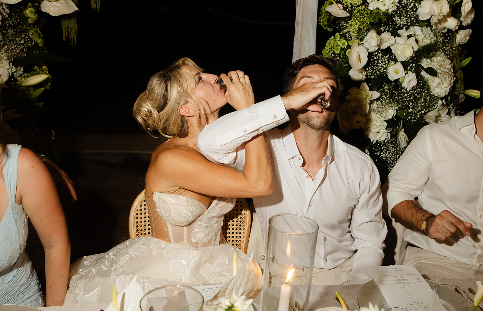 Bride and groom taking tequila shots during outdoor wedding reception in Mexico